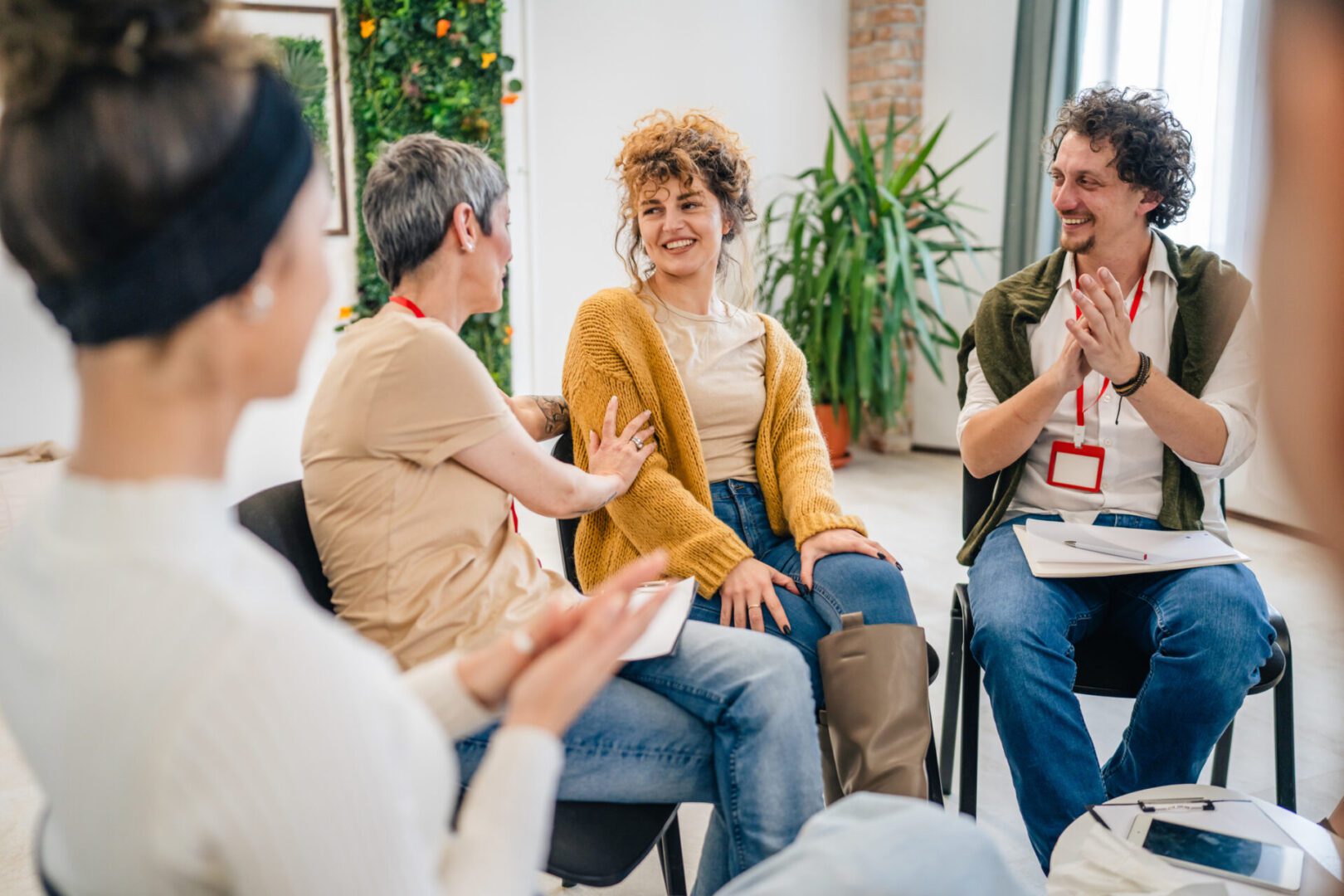 Support Group with Therapists and Woman in Focus solving problem Group discussing and clapping in a meeting.
